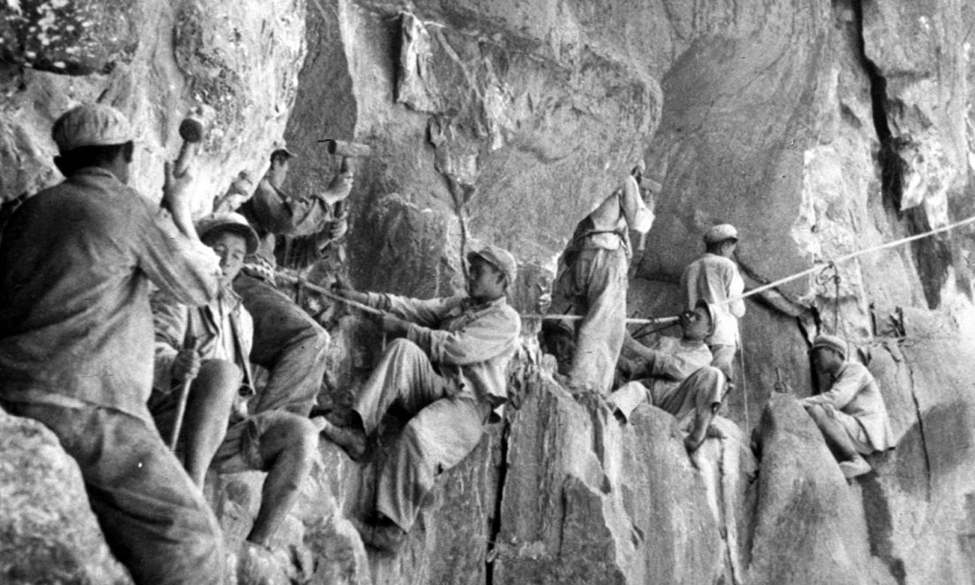 1954年，修筑康藏公路的解放軍戰(zhàn)士們在怒江兩岸的懸崖陡壁上辟山筑路。新華社稿 李萬春、張加里攝